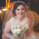 bride in white dress with bouquet sitting in vintage chair and smiling
