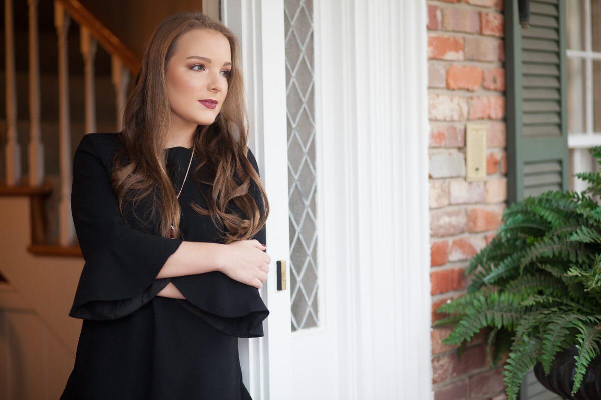 beutiful brunette senior portrait in home's front doorway