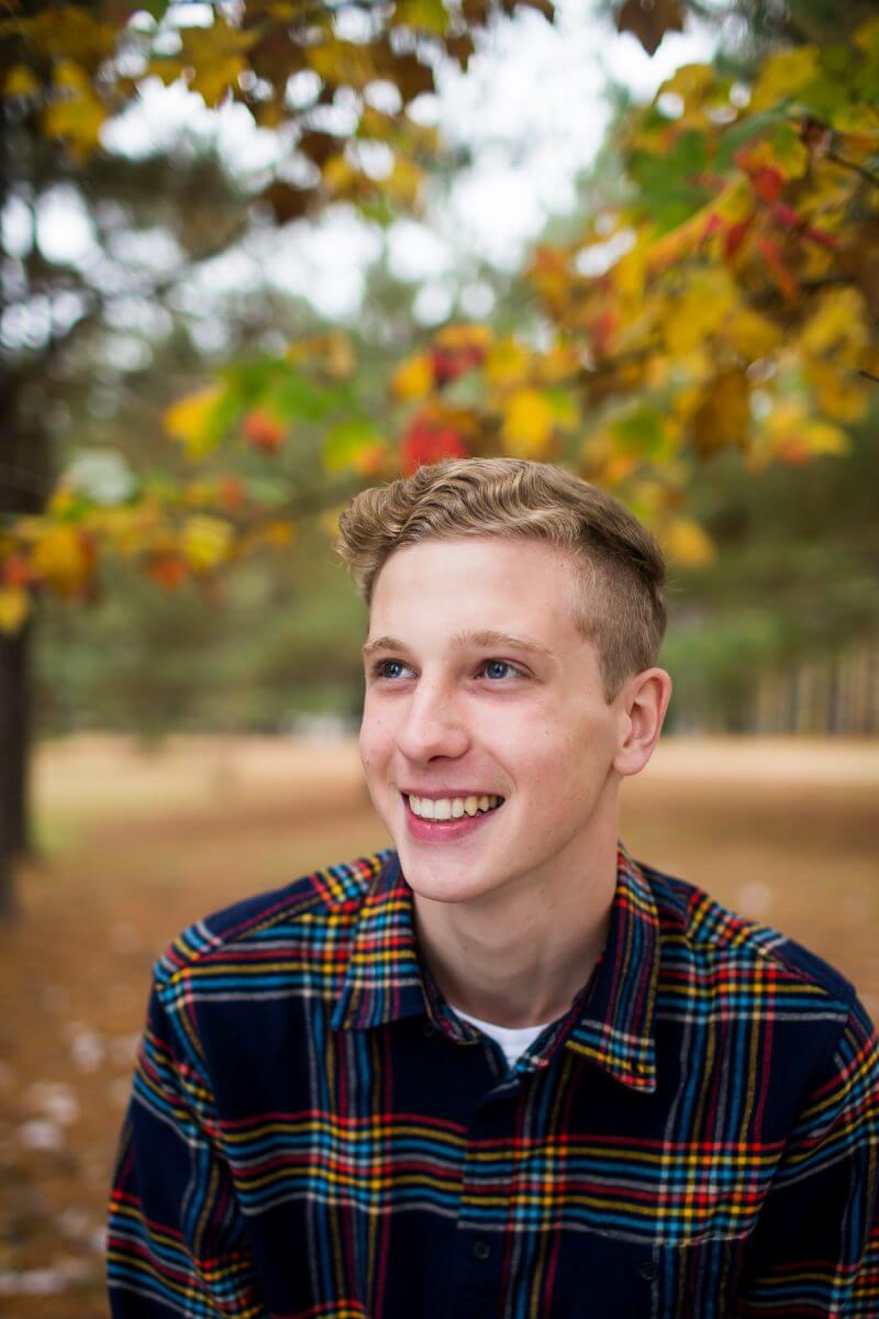 smiling senioe boy portrait in bright plaid shirt