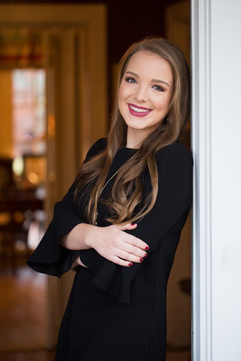 high school senior girl in black dress standing in doorway and smiling
