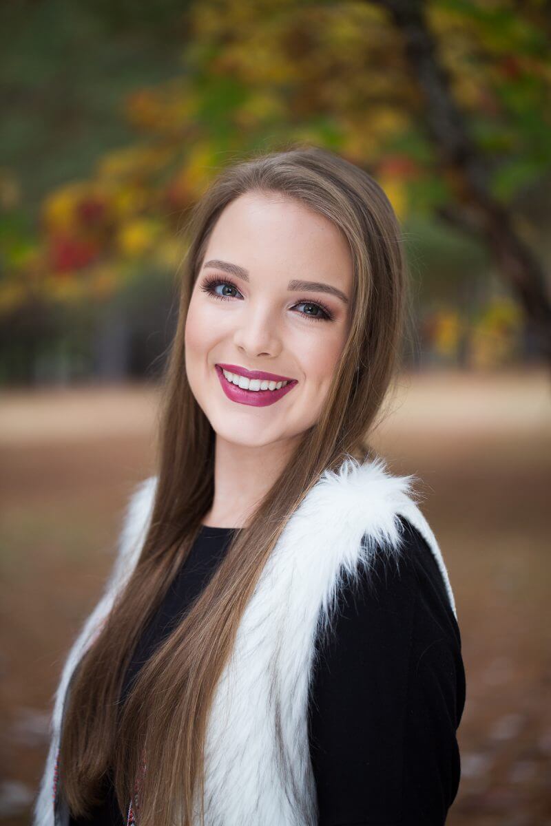 brunette high school senior headshot with fall foliage