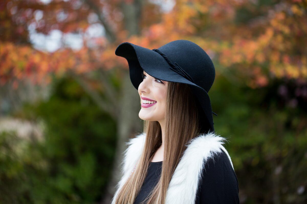 pretty smiling senior girl in fluffy vest and black floppy hat