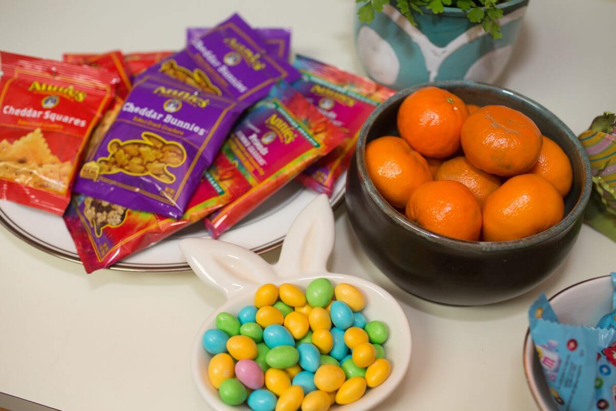 pastel M&Ms, oranges, and packets of crackers arranged on counter top
