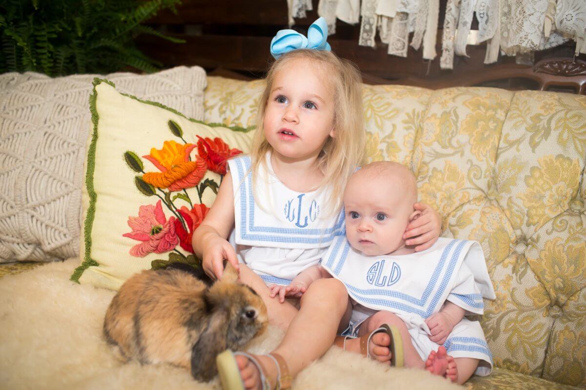 young child and infant pet tan rabbit on vintage couch