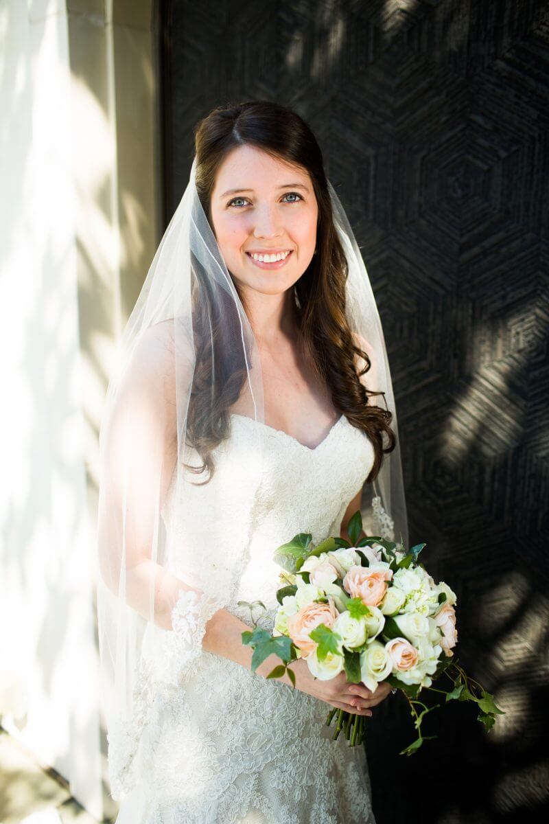 Smiling bride with bouquet posing in front of decorative doors