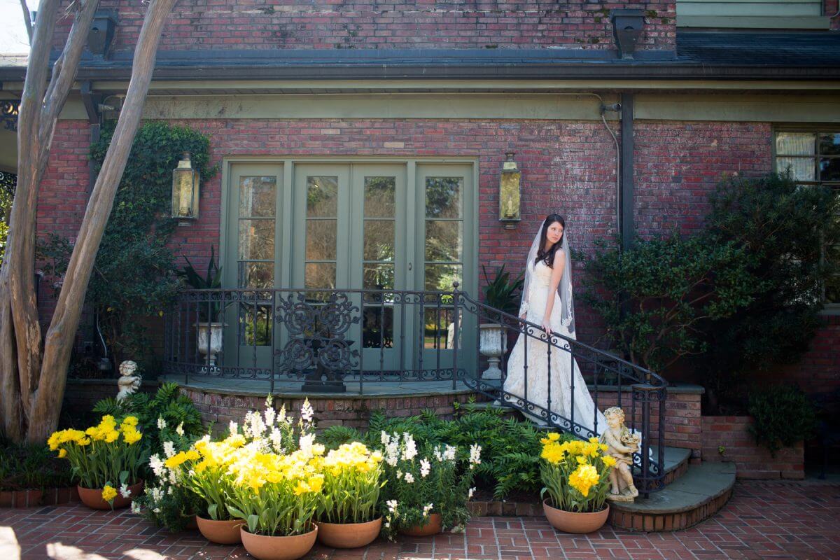 Panoramic view of bride in wedding dress ascending steps to balcony