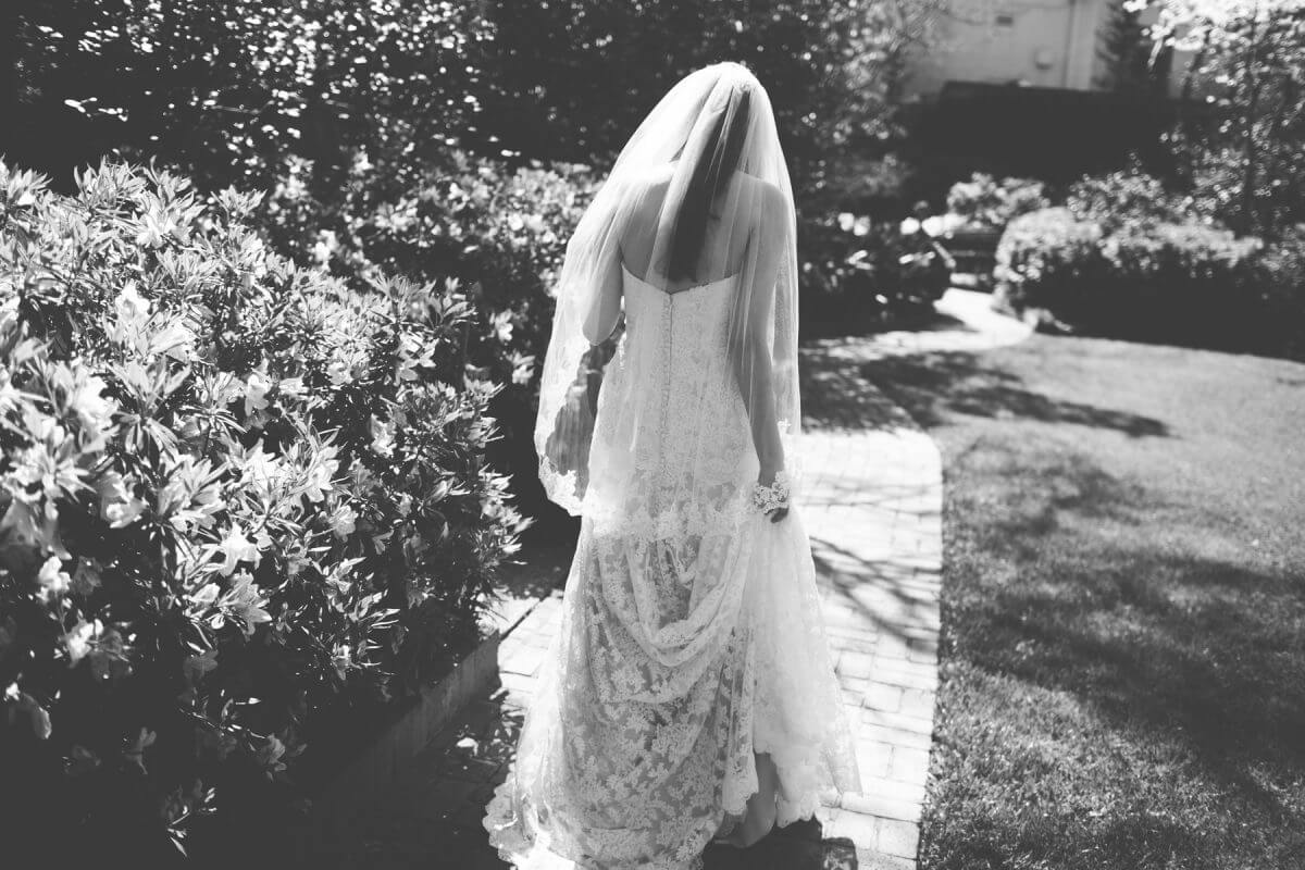 Bride in wedding dress walks away down garden path