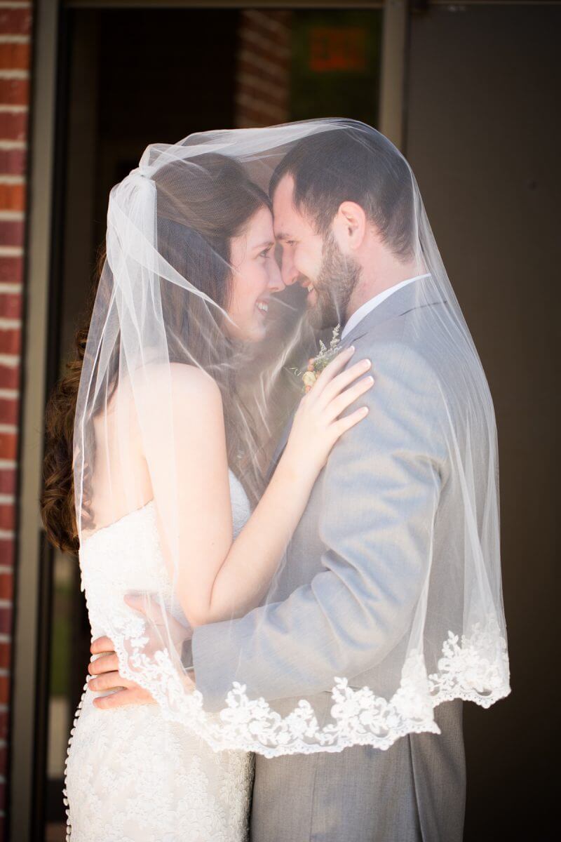 bride and groom staring into one another's eyes covered in bride's wedding veil