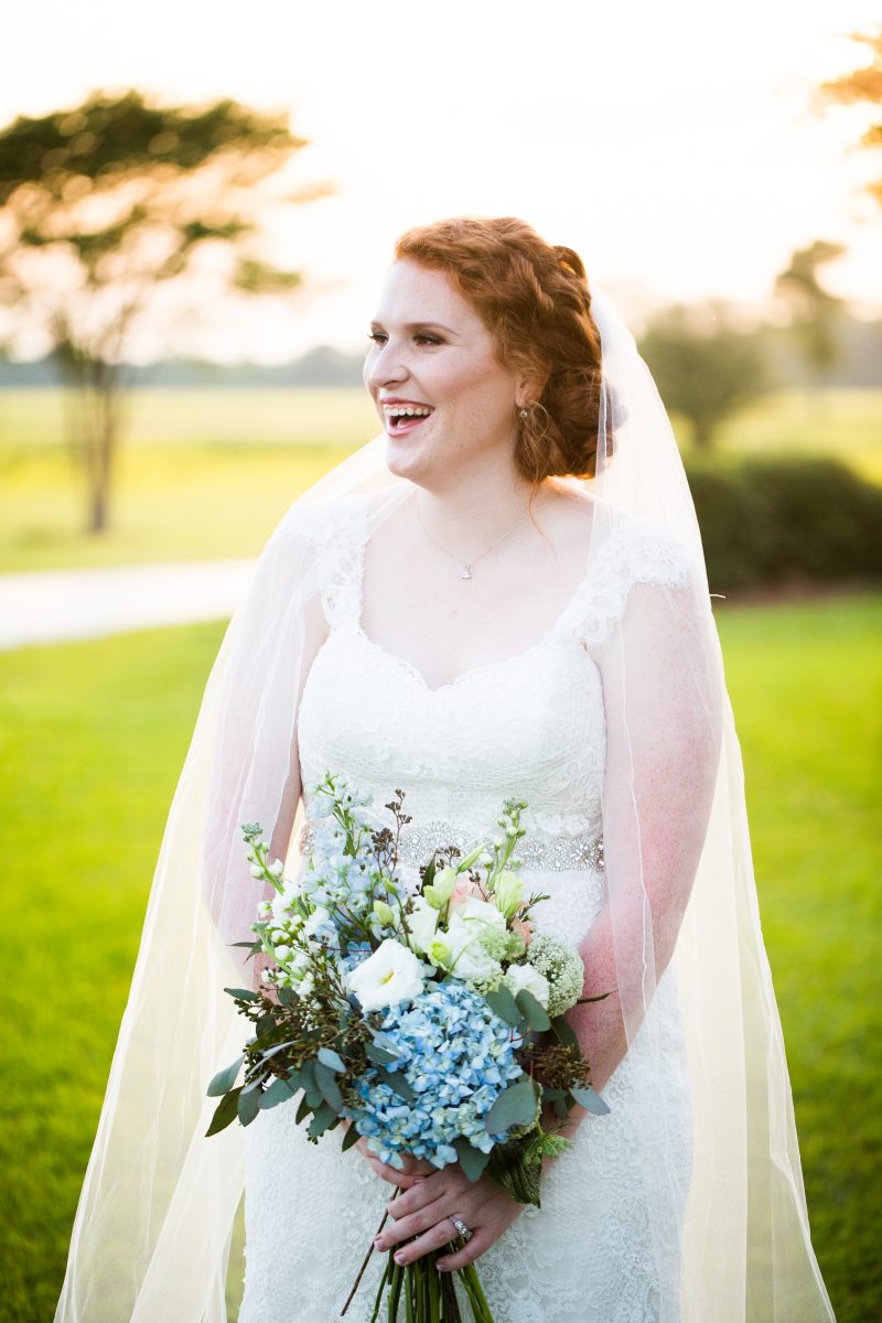 red headed monroe louisiana bride with long veil laughing while holding bouquet