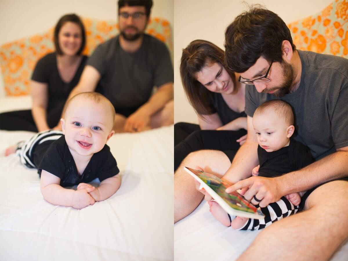 baby on bed smiling with parents in background and father reading baby a book on bed
