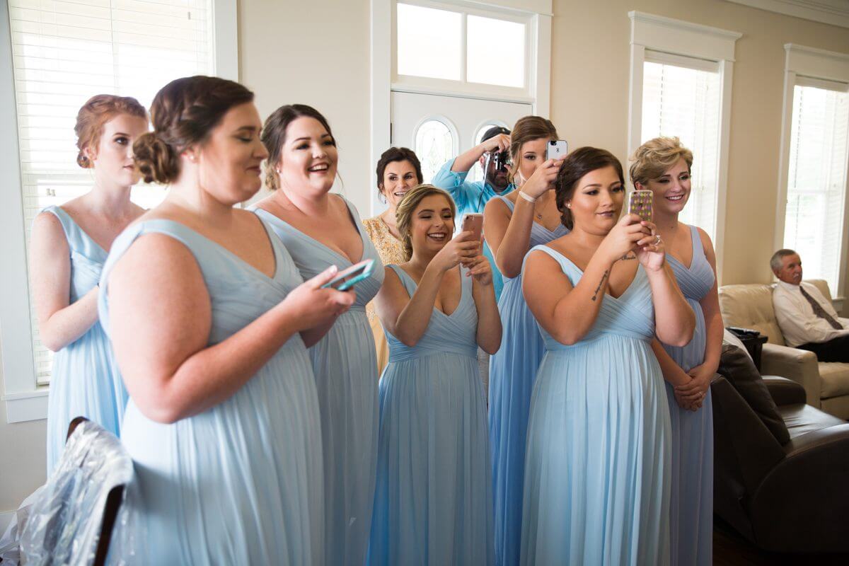 brides maids in blue dresses using cell phones to photograph bride in ruston, LA