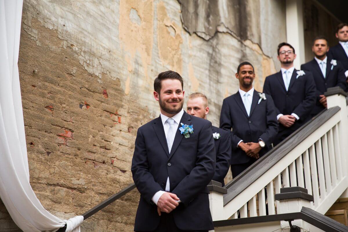 Groom and groomsmen standing on stairs waiting for wedding ceremony to begin