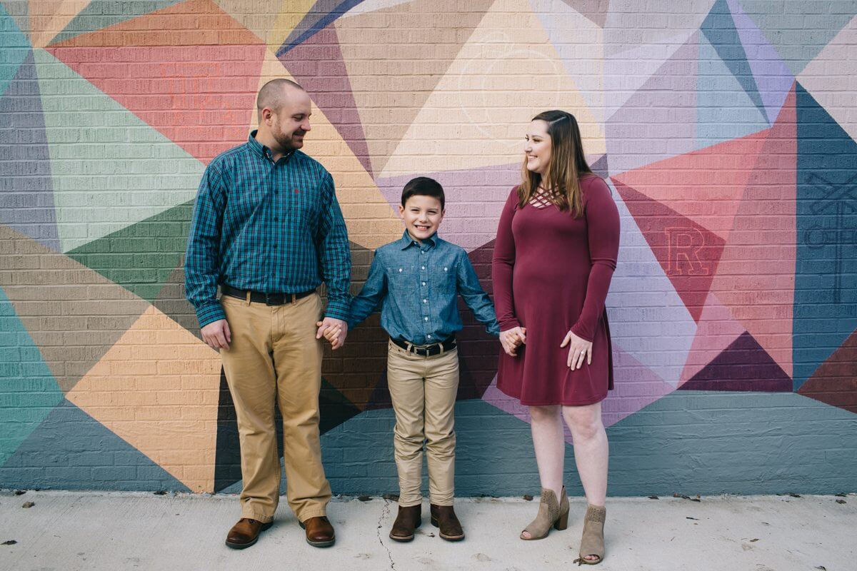 Engaged couple and son in front of mural in downtown Ruston, Louisiana.
