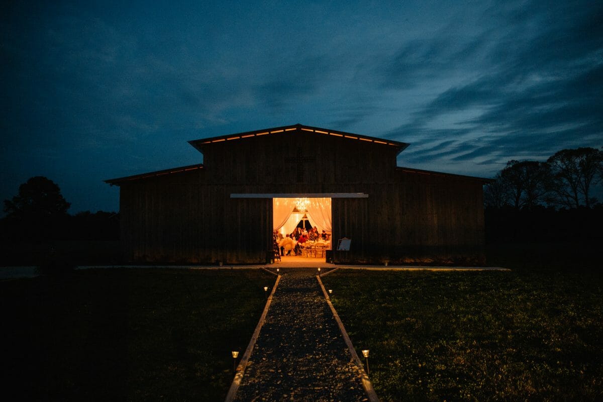 The Wedding Barn at Eros at night with the front doors open and people dancing inside. One of the popular North Louisiana Wedding Venues.