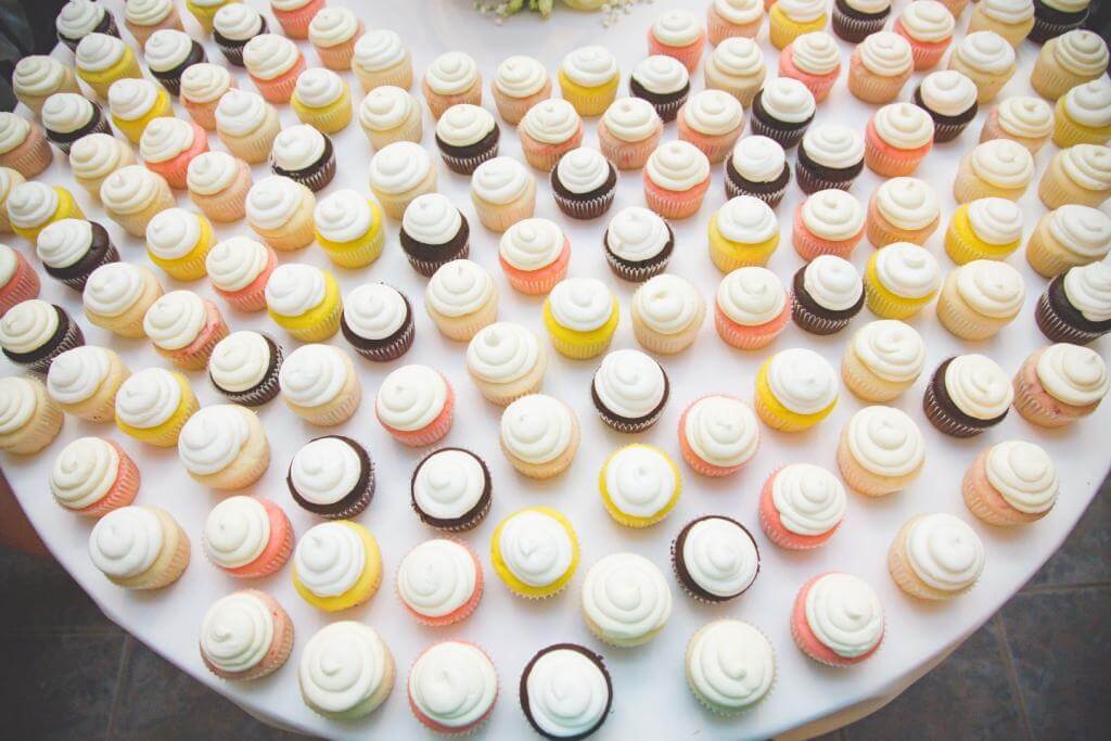 aerial view of assorted colors, white frosting cupcakes sitting on a round white table
