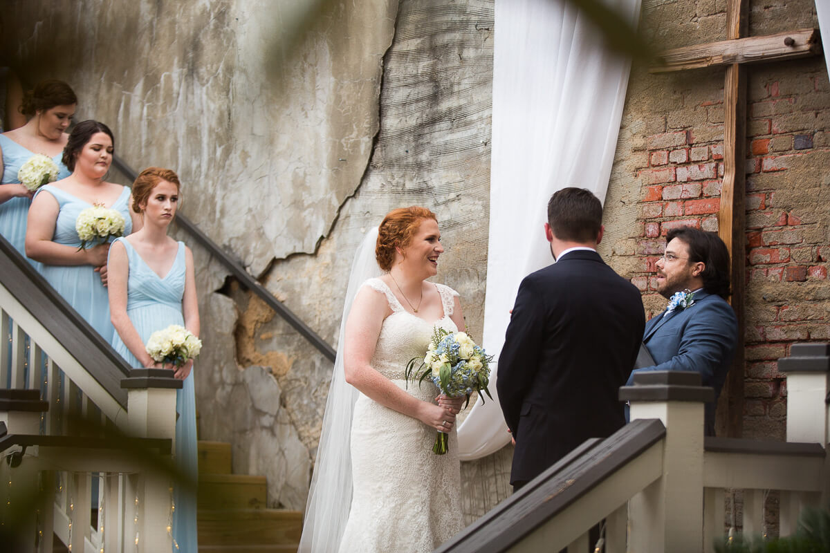 smiling bride and groom standing before pastor on dais at the Norton Building in Ruston, Louisiana