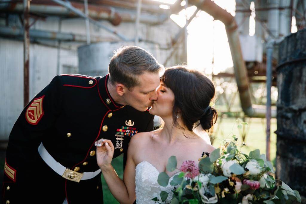 marine groom kissing bride in wedding dress